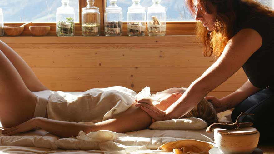 persona stesa a terra che viene massaggiata da una donna con le mani sulle spalle